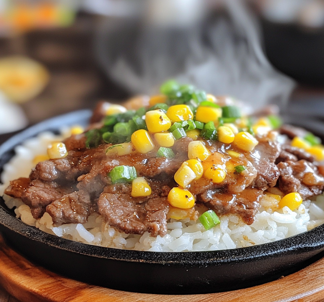 A sizzling hot plate of homemade beef pepper rice with thinly sliced beef, white rice, corn, green onions, and black pepper, served on a cast iron skillet with steam rising.